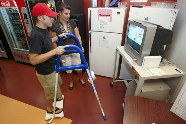 Shane Robb, left, tries out Adriane Boynton's We Can Stand invention while virtual snow skiing on her Wii video system Thursday during the annual student Assistive Technology Fair at Touro University.