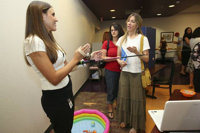 Jamie Hall explains to Jakki Ruzich and Anne Evans, center,how her hands-free fishing pole invention helps disabled fisherman during a student Assistive Technology Fair at Touro University.