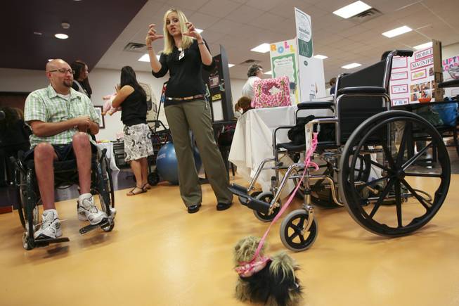 Allison Stone discusses how she invented the roll-along dog walker with Henderson resident Cameron Stay, left, during the annual student Assistive Technology Fair at Touro University.