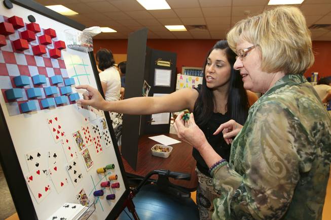 Karen Picus, director of the Occupational Therapy School, listens as Belinda Garey demonstrates her magnetic sdaptive table games Thursday during the annual student Assistive Technology Fair at Touro University.