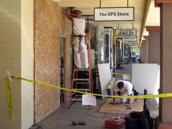 John Bolton, left, and Nick Duran, from A. Duran Construction, board up the front of the UPS Store on South Rancho Drive after Nevada Supreme Court Justice Kris Pickering's car went through the front of the store.