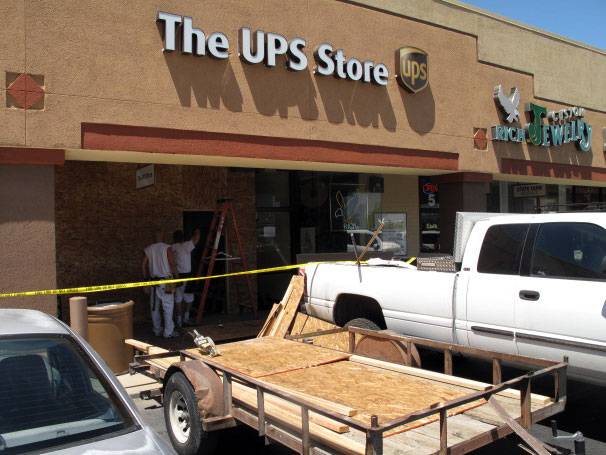 John Boulton and Nick Duran, from A. Duran Construction, board up the front windows of the UPS Store on South Rancho Drive after Nevada Supreme Court Justice Kris Pickering's car went through the front of the store.