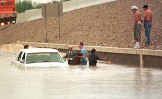 Stranded motorists remove belongings from a submerged car in a flooded underpass on Jones underneath U.S. 95 on July 8, 1999. Three inches of rain fell Thursday afternoon causing the worst flooding in the city since 1984, according to a spokesman for the National Weather Service. 