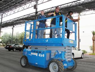 Lane Beckwith (center) of solar panel maintenance company IE Systems take students Brandon Williams (left) and Diego Ruvalcava (right) on a brief trip in a scissor lift so they could examine the solar panels installed on parking shade structures at TWC Construction in Henderson.