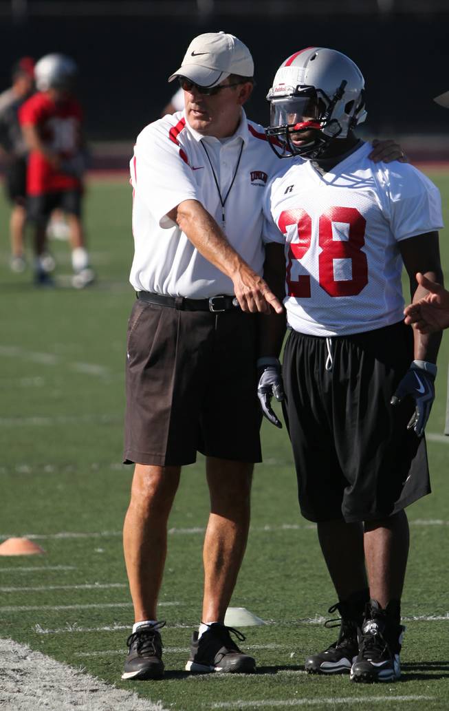 Head coach Mike Sanford instructs Bradley Randle during the football team's first practice at Rebel Park on Thursday morning.