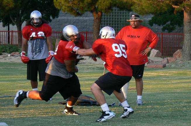UNLV defensive line coach Andre Patterson (far right) watches while Alex Klorman (95) uses boxing gloves during a drill against an unidentified teammate on Sunday. Patterson created the drill, which is designed help defensive lineman keep the opposing offensive lineman's hands down, while coaching with the Minnesota Vikings.