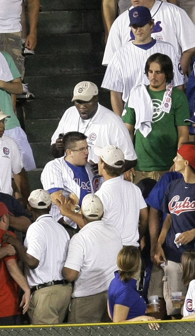 A baseball fan is ejected by security after a beverage was poured on Philadelphia Phillies center fielder Shane Victorino while catching Chicago Cubs' Jake Fox's sacrifice fly during the fifth inning of a baseball game Wednesday, Aug. 12, 2009, at Wrigley Field in Chicago. Sean Marshall scored on the play.