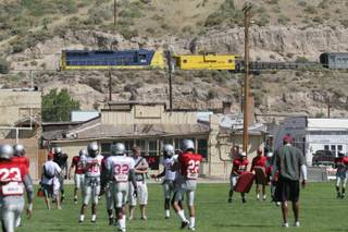 A train passes across the mountains off in the distance during the opening portion of UNLV's Thursday morning practice at Broadbent Park in Ely.