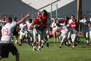 UNLV defensive end Malo Taumua jumps on the back of fellow end Jason Beauchamp after he caught a fly ball off the Jugs machine to close out Sunday evening's practice at Broadbent Park in Ely. Five of eight selected linemen needed to catch a fly ball to help the Rebels avoid conditioning after practice. Beauchamp's grab was the clincher.