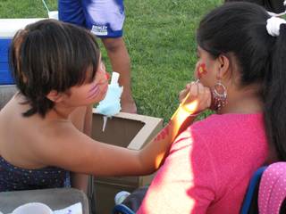 Nora Scanlon paints a flower on Cynthia Huendo during the annual back-to-school event at Hartke Park on Sunday.
