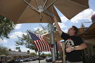Terry Stevens lowers the patio umbrellas at the Coffee Cup in Boulder City.
