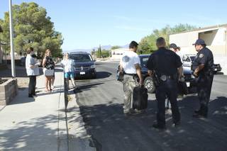 Neighbors stand by as Boulder City Police officers and narcotics detectives gather Friday outside the property at 1733 Red Mountain Drive following a drug raid.  Methamphetamine and drug paraphernalia were seized and the residents were arrested on drug-related charges, authorities said.  