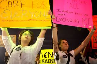 Demonstrators gather while holding signs Thursday night during a Health Insurance Reform Now rally in Las Vegas.