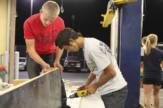 After a late start, seniors Tim McKeever and Allen Haines, right, get to work drilling the sides of their boat for the senior homecoming float Monday night at Boulder City High School.
