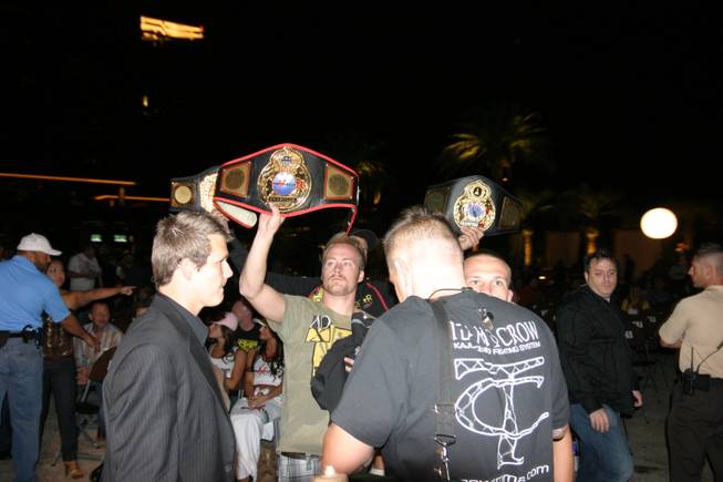 The cornermen from Casey Johnson's team hold up his various championship belts.