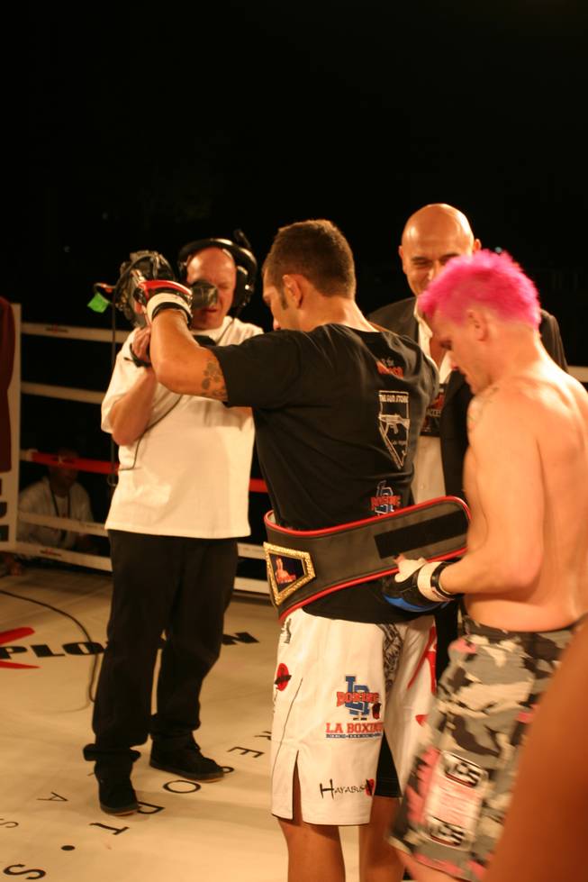 Steve Sharp places the lightweight belt around the waist of his opponent John Gunderson at MMA Xplosion at the M Resort.