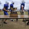Basic High School varsity football players run past the Henderson Bowl trophy during practice on Monday afternoon.