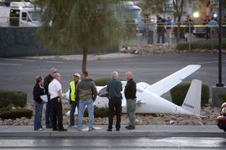 Investigators look over an experimental plane after the pilot made a forced landing on Rancho Drive near Texas Station on Friday, Oct. 30, 2009.