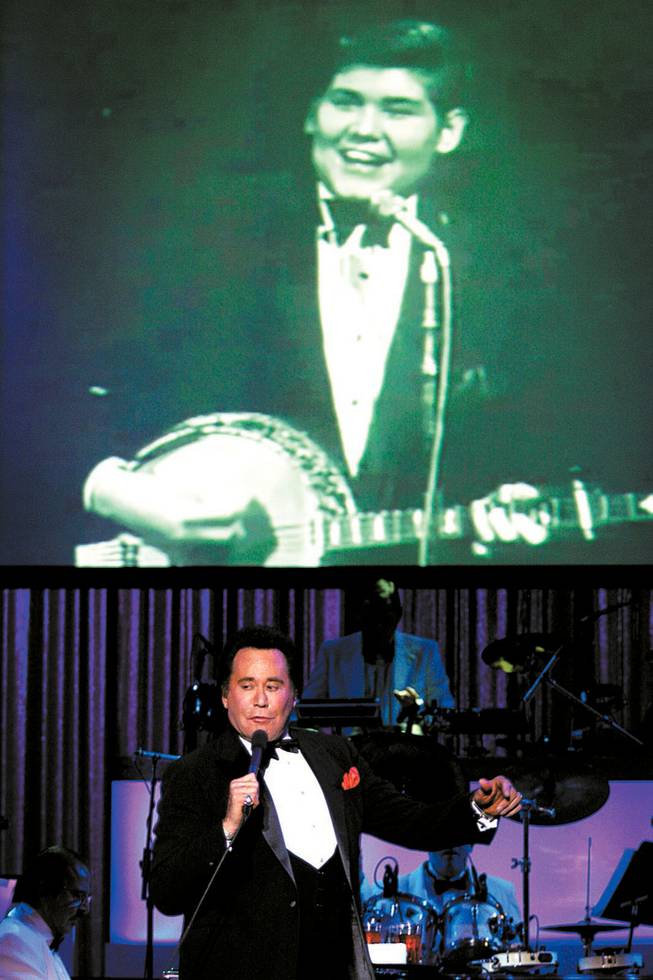 
Wayne Newton performs as a photo of him as a young man flashes on the screen during the opening night performance Wednesday of "Once Before I Go" at the Tropicana. The show traces Netwon's career and has him singing duets with the likes of Sammy Davis Jr. and Dean Martin, who appear on video screens.