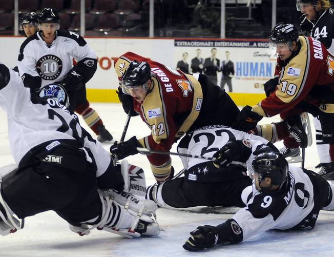Condors defenseman John de Gray (center) lunges over the top of Chris Neiszner to dig for a loose puck in front of Wranglers goaltender Michael Ouzas as defenseman Mike Madill sprawls out as a last line of defense during the first period of action on Thursday night.