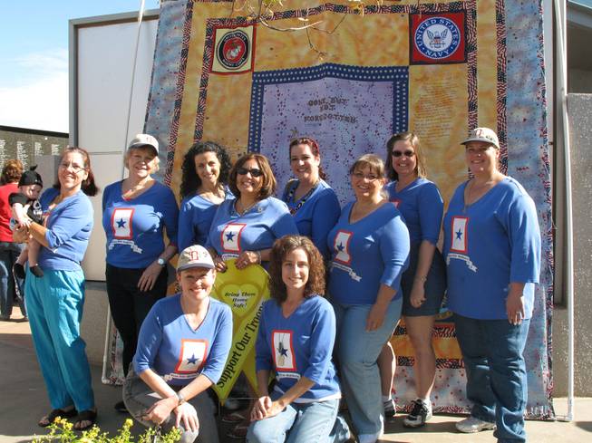 Members of the Henderson and Boulder City chapter of Blue Star Mothers take a group picture in front of a quilt honoring veterans outside the Henderson Veterans Memorial Wall on Saturday.