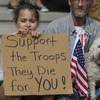 Alexis Gaskin, 9, holds a sign in support of her family while sitting with her grandfather, Doug Wee