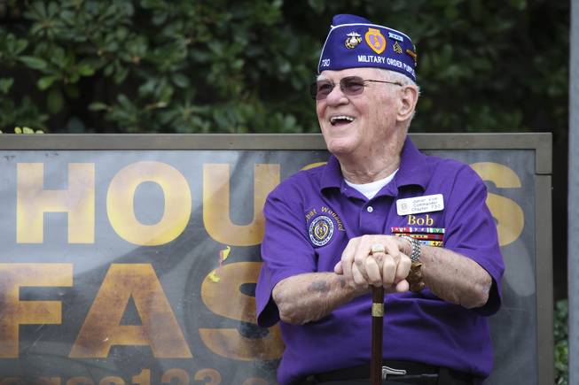 Due to a leg injury, retired U.S. Marine Corps Maj. Bob Freeman, who has received many purple hearts, sits on a bench waiting to join the Chapter Military Order of Purple Hearts in their march in the Veterans Day parade Wednesday in downtown Las Vegas.