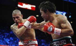 Miguel Cotto (L) takes a punch from Manny Pacquiao during their WBO welterweight title fight Saturday at the MGM Grand Garden Arena.
