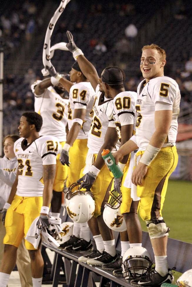 Wyoming freshman quarterback Austyn Carta-Samuels (5) and his teammates celebrate on the sidelines during the closing moments of the Cowboys' 30-27 victory at San Diego State. Sparked by a 24-0 scoring run in the fourth quarter, Dave Christensen's club improved to 5-5 and kept its postseason hopes alive.
