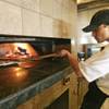 Head cook Christian Guzman slips a pizza into the oven at the newest Sammy's Woodfired Pizza in Las 