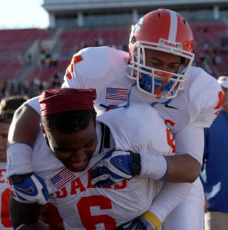 Bishop Gorman's Martin Tomaika jumps on the back of teammates Xavier Grimble Saturday in celebration of the Gaels 62-21 victory against Del Sol in the large-school state title game at Sam Boyd Stadium.