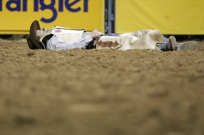 Cody DeMoss lands on the ground, uninjured, after being thrown from his saddle bronc during the 10th and final go round of the 2009 National Finals Rodeo Saturday, Dec. 12, 2009, at the Thomas & Mack Center.