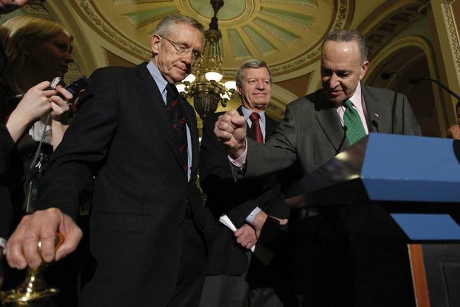 Senate Majority Leader Harry Reid of Nevada, left,  listens as Sen. Charles Schumer, D-N.Y., right, drives home a point while answering questions on Capitol Hill in Washington, Thursday, Dec. 24, 2009, after the Senate passed the health care reform bill. Senate Finance Committee Chairman Sen. Max Baucus, D-Mont., is at center.