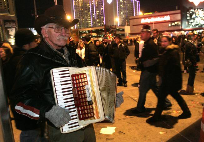 Dean Burke plays his accordion on the Strip as thousands ...