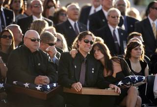 Steven Bentley Cooper, left, and Marshall Cooper, who is being comforted by his wife, sit in the front row during the funeral services for their father, the slain court security officer Stanley Cooper outside of Central Christian Church in Henderson Monday, January 11, 2010.