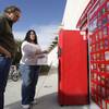 Donna Hurd, a Redbox merchandiser,  shows library patron Tim Larson how to use a promo code for new customers at a Redbox DVD movie rental kiosk in front of the Paseo Verde Library in Henderson on Tuesday. The Paseo Verde Library and the Green Library recently added the rental kiosks.