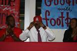 After signing his letter of intent to play football at Arizona, Valley High's Garic Wharton slips on an Arizona cap.