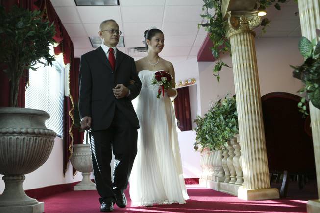 Rizalino Bombio walks his daughter, Millin Grace Bombio, of London, down the aisle during her wedding on Valentine's Day 2010 at the Little White  Wedding Chapel in Las Vegas.
