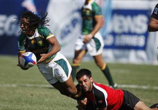 South Africa's Cecil Afrika passes as he is taken down by Canada's Philip Mack during the USA Sevens World Series rugby tournament, Saturday, Feb. 13, 2010, in Las Vegas.