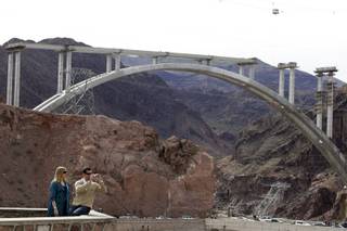 Jason and Rachel Burger of Lynchburg, Virginia take photo at an overlook of the Hovver Dam, with the bypass bridge construciton in the background, outside Boulder City Friday, February 26, 2010.