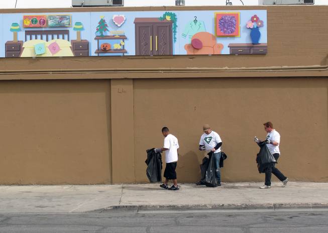 From left, Omar Urrutia, Paul Grimyser and Daniel Gamble pick up trash Saturday under a mural in the Arts District as part of the Great Las Vegas Cleanup.