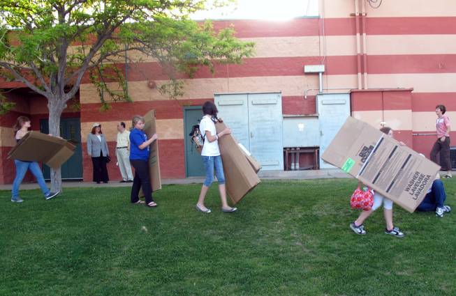 A group of volunteers carry their cardboard boxes to get ready to sleep outside as part of a fundraiser for Family Promise at the Boys and Girls Club.