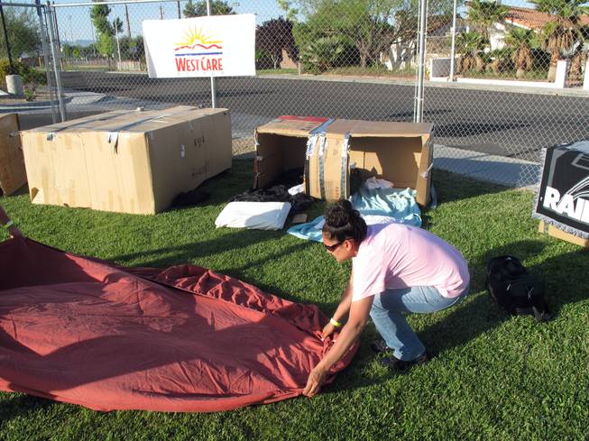 Julie McGinley sets out a sheet to sit on the grass outside her cardboard box, where she will sleep Saturday night to get an idea what it is like to be homeless.