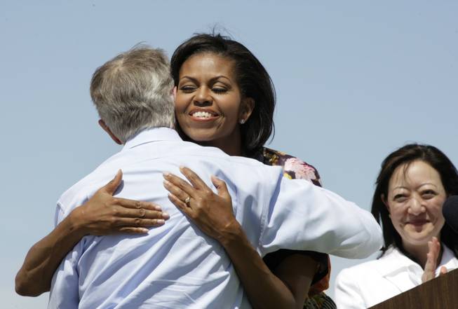 First lady Michelle Obama, center, gets a hug from Senate Majority Leader Harry Reid as she is introduced to speak Tuesday at the Red Rock Canyon National Conservation Area. Assistant Secretary of the Interior Rhea Suh looks on at right. Obama, Reid, and Suh kicked off the national "Let's Move Outside!" initiative that promotes outdoor physical activity for children and families.
