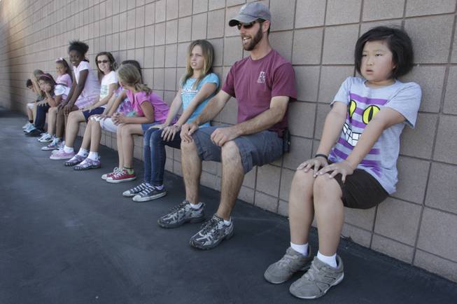 Physical education specialist Brian Sigler joins fourth grader as they demonstrate wall sits during a physical education class at Twitchell Elementary School in Henderson Friday, June 4, 2010.
