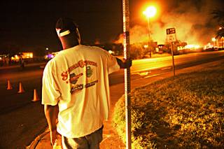 Sann Atkins, 36, of Las Vegas stands at the corner of Boulder Highway and King Street watching a four-alarm fire at a pallet yard across the street. Atkins is part owner of the Legacy Auto Shop, which is across the street from the yard that caught fire Tuesday.  Police and firefighters were not allowing anyone near the blaze, so at the time of the photo, Atkins did not know whether his shop had been damaged.