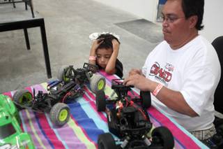 Kalei Bowman works on his remote-control cars as his 4-year-old grandson Jayme Caudoy waits for his turn to drive Wednesday at the 702 RC Raceway in Las Vegas.