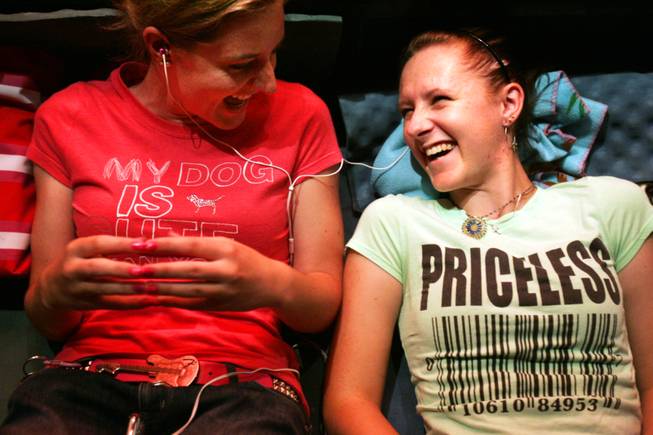 Kristi DeVita, left, and her friend Katie Ritchie, both of Boulder City, share ear buds and listen to music while waiting in line for the new iPhone 4 outside the Apple store in Town Square in Las Vegas Wednesday, June 23, 2010. The store opened at 7 a.m. Thursday, June 24.