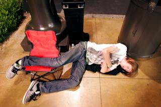 Alex Asay, 13, of Las Vegas takes a nap by a trash can while waiting in line for the new iPhone 4 just before sunrise outside the Apple store in Town Square in Las Vegas Thursday, June 24, 2010. The store opened at 7 a.m.