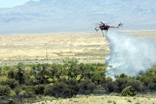 A firefighting helicopter drops water on a brush fire in the Warm Springs area of Moapa, July 2, 2010.
